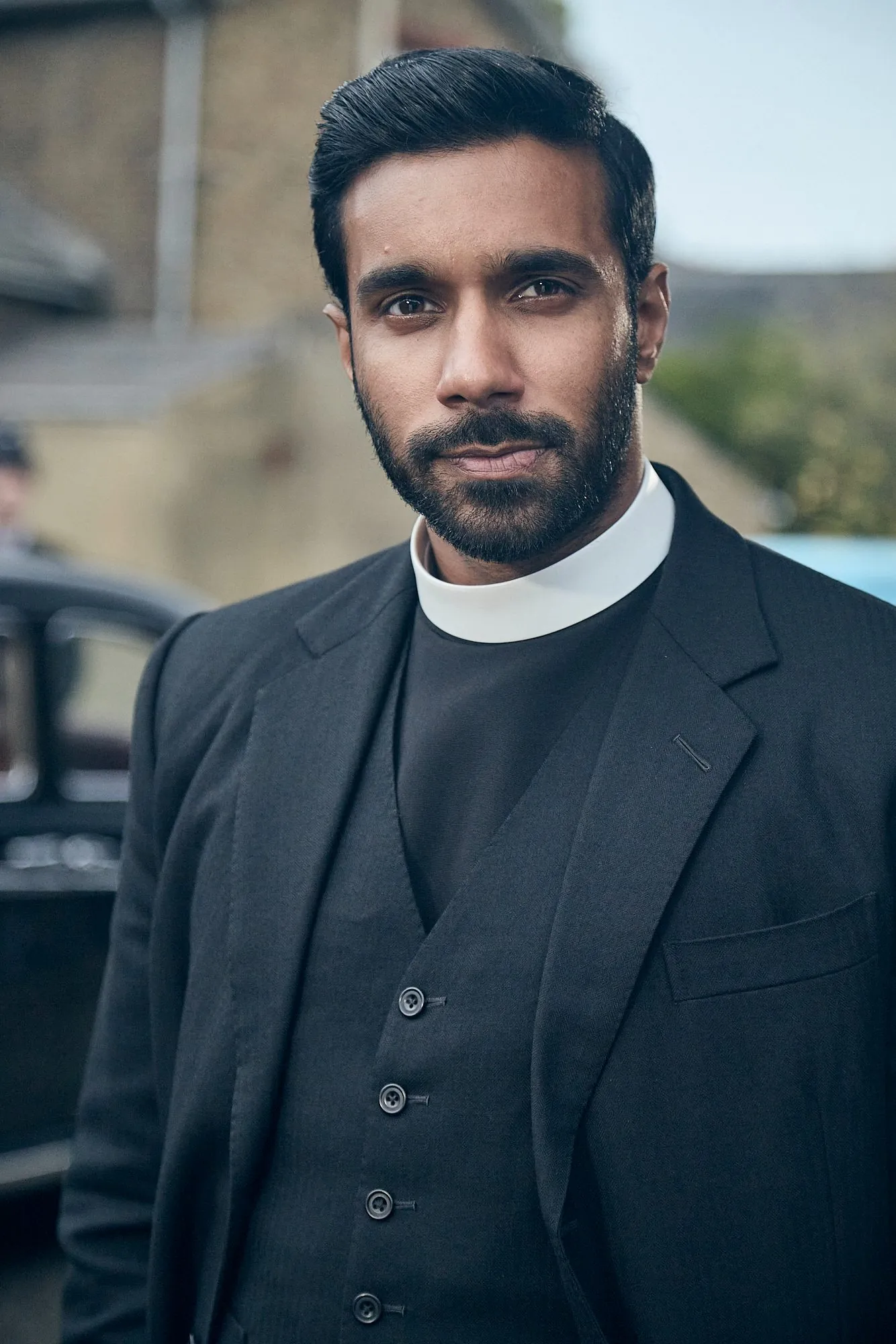 A vicar in clerical collar on a village street in Grantchester